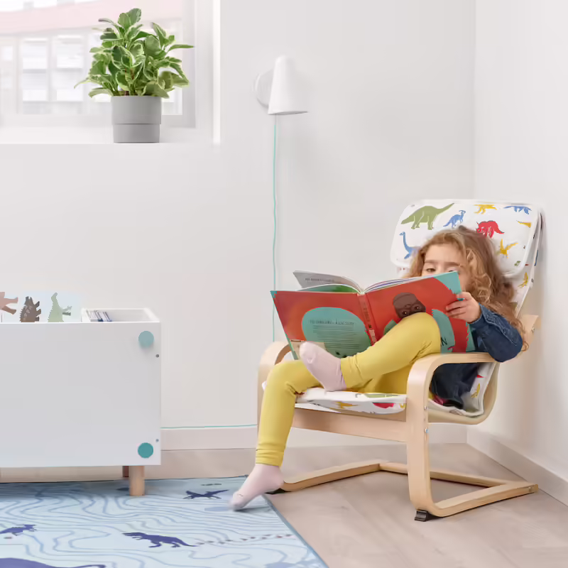 A child sits in a small armchair reading.