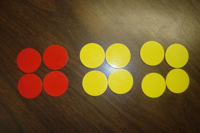 Three piles of four counter chips each, one pile red and two yellow