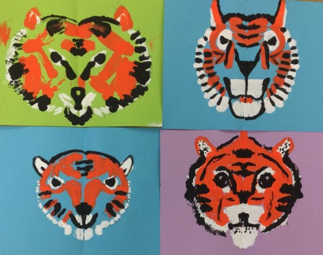 Symmetrical tiger faces printed with paint on colored backgrounds (Second Grade Art)