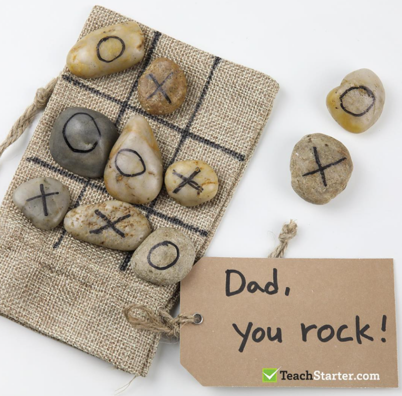 A burlap bag has rocks on top of it with Xs and Os drawn on them. The tag says, "Dad, you rock."