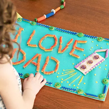 A picture is made from macaroni and says I love dad.